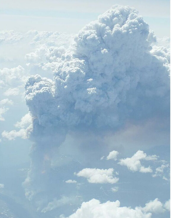 Large smoke clouds in the sky amongst normal clouds.