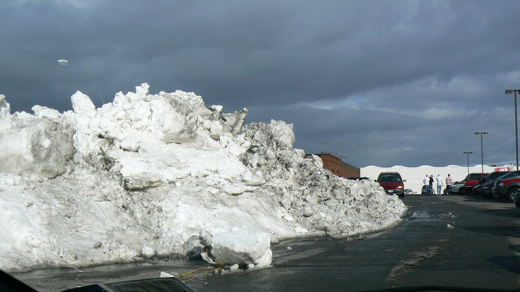 photograph of a parking lot with a massive pile of snow from plowing.