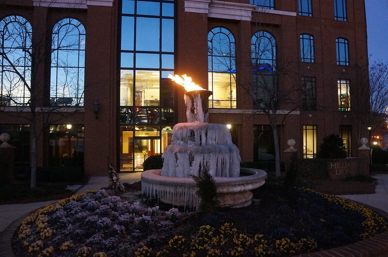 A photograph of an outdoor fountain in which the water cascading over the edges of the fountain has frozen.