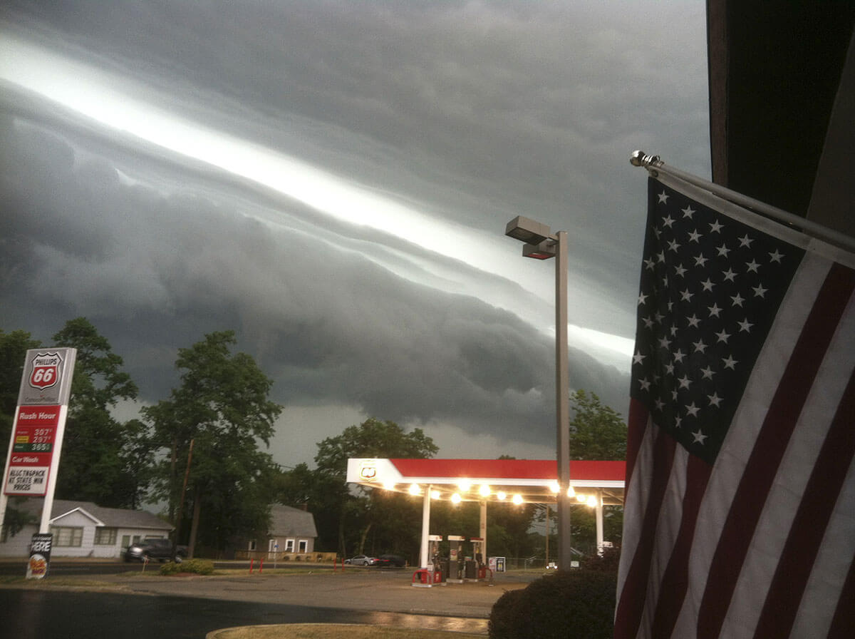 Photograph shows a shelf cloud on the leading edge of a severe derecho storm system.