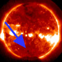 Image from video shows orange Sun, with bright blotches across center, and tiny black spot, which is Venus, near bottom center, with large blue arrow pointing to it.