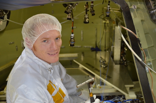 Levi Smith sits in the Exploration Flight Test 1 Crew Module with a calibrated tap test hammer during a series of environmental tests he supported prior to launch.