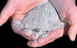 Person's hands holding a pile of very powdery, gray volcanic ash.