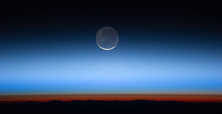 The moon seen at dusk over the horizon.
