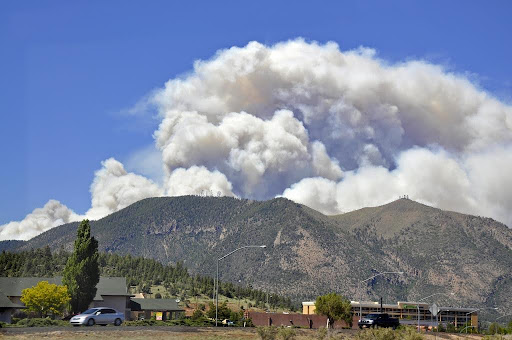 A cloud of smoke seen coming from behind a mountain range.