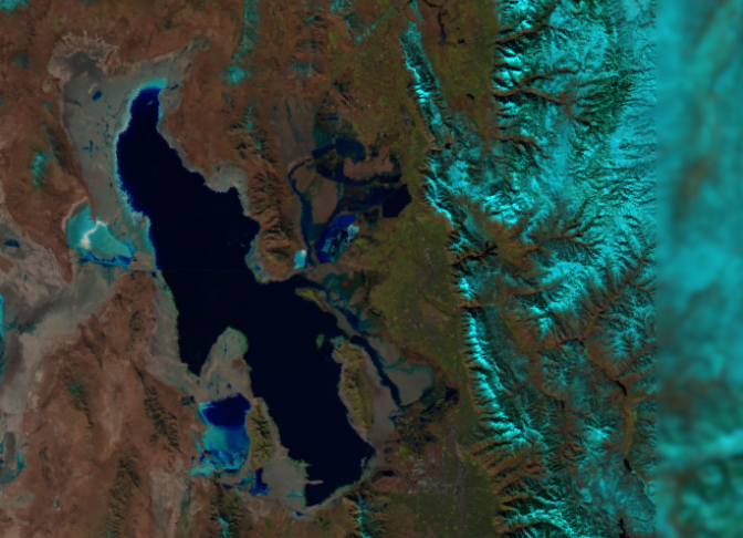 Satellite image of the Great Salt Lake, Utah, showing dark blue water surrounded by brown land and snow-capped mountains on the right