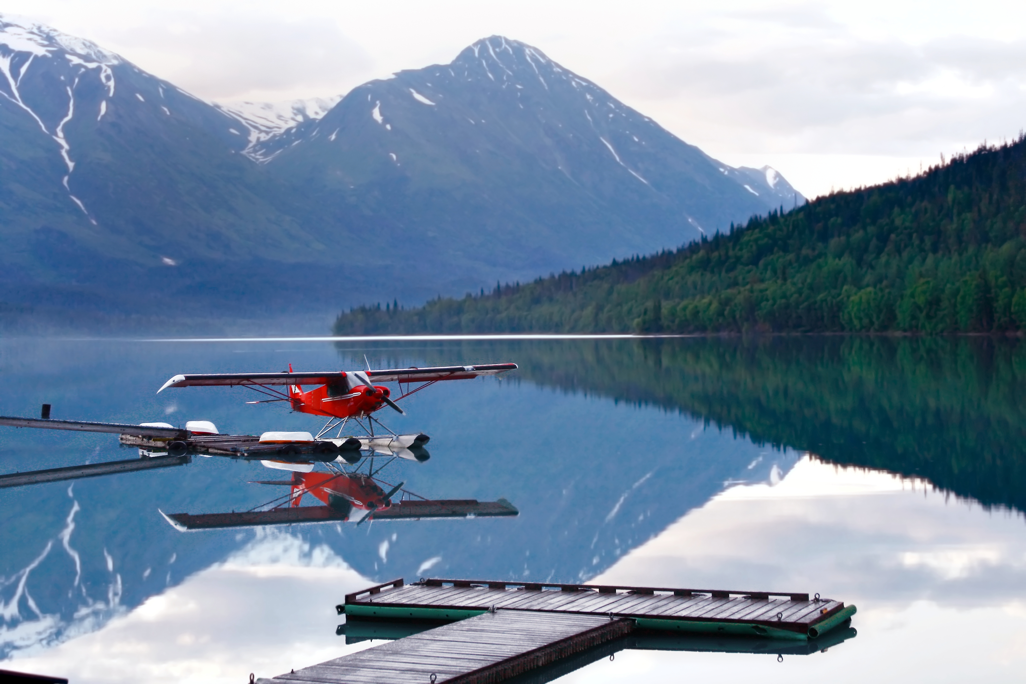 A plane seen on a glacier lake with mountains in the background.